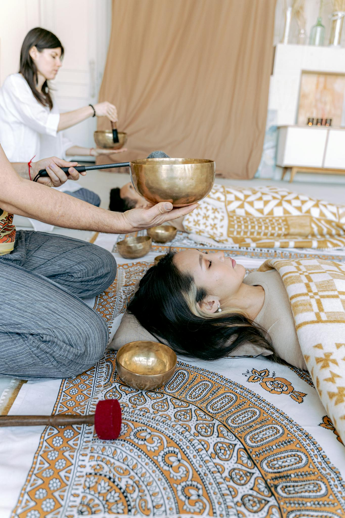Woman experiencing relaxation with Tibetan singing bowl therapy indoors.
